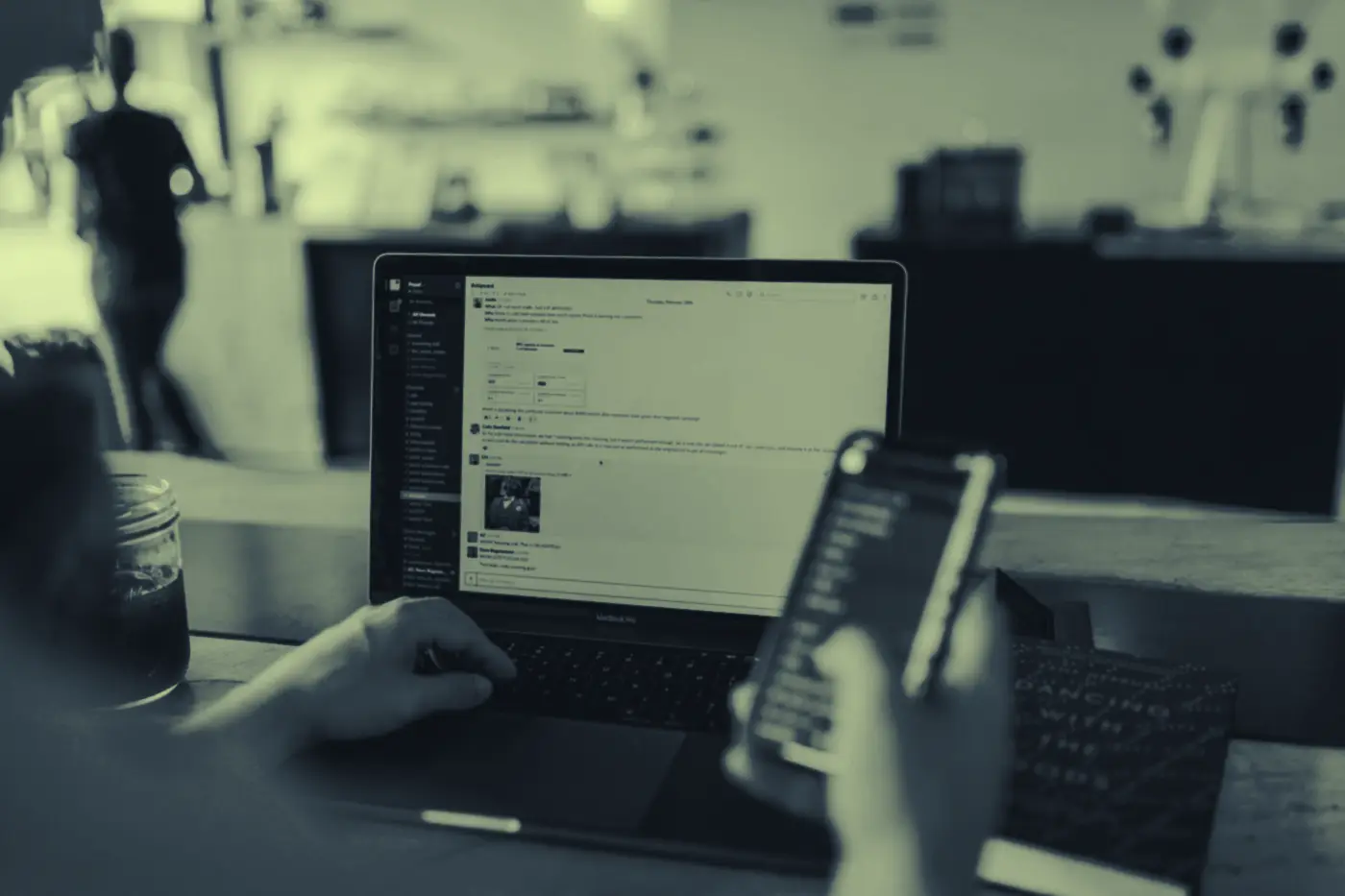 Persona usando una app financiera en su teléfono frente a un portátil
